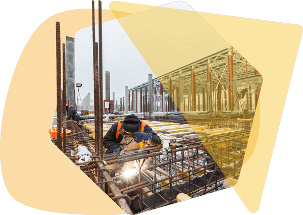Construction crew welding on a commercial project while using document management software to track field approvals and job specs